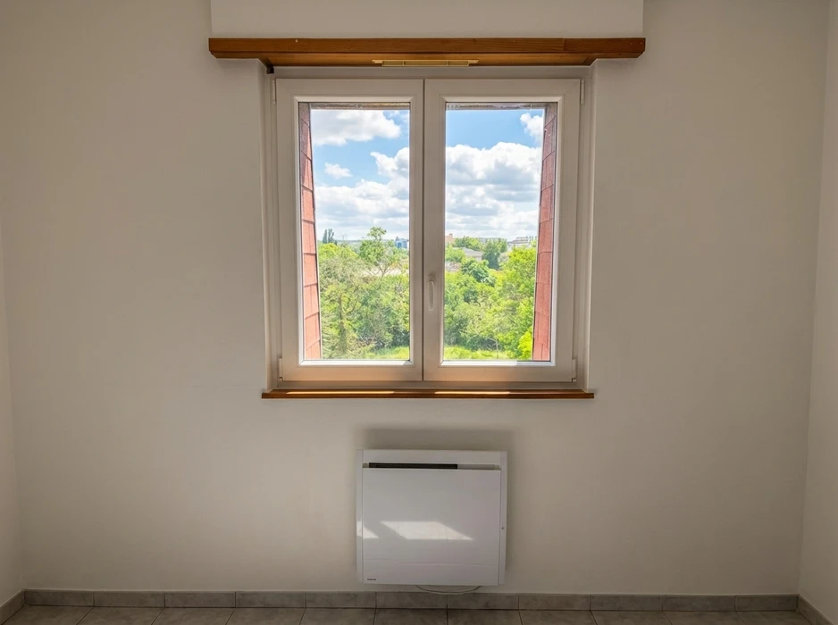 Intérieur en rénovation, mur enduit beige avec une fenêtre à soufflet (oscillo-battante) à châssis PVC blanc, format horizontal panoramique