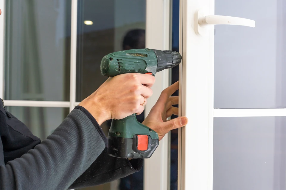 Gros plan sur les mains du menuisier avec cadenas pendant l'installation du processus de verrouillage dans la porte en bois