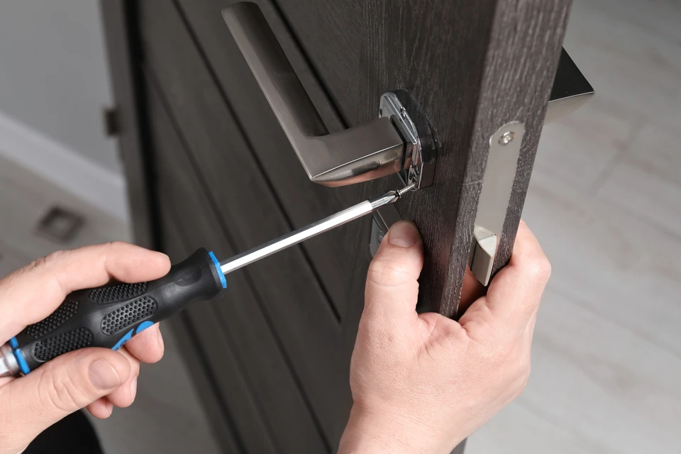 Gros plan sur les mains du menuisier avec cadenas pendant l'installation du processus de verrouillage dans la porte en bois