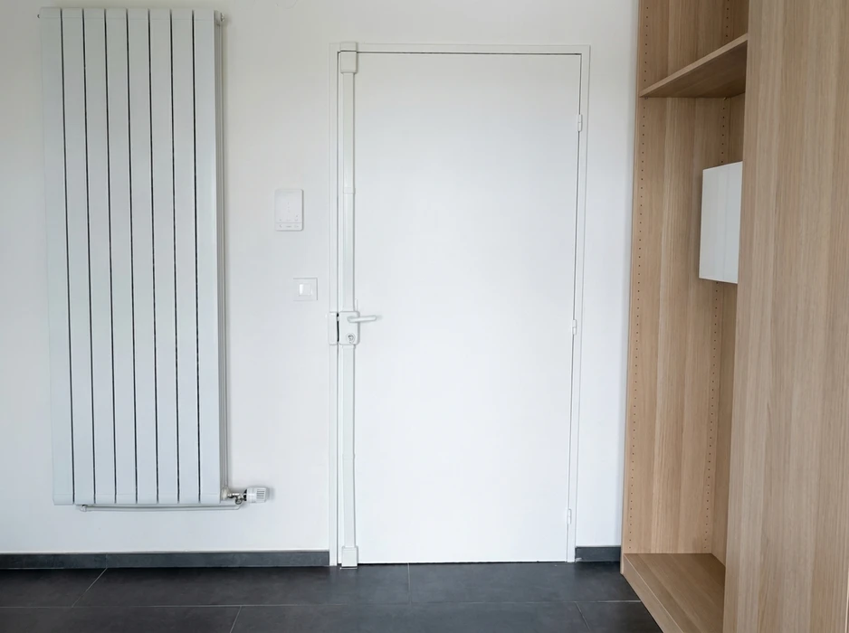 Intérieur en rénovation, mur enduit beige avec une fenêtre à soufflet (oscillo-battante) à châssis PVC blanc, format horizontal panoramique
